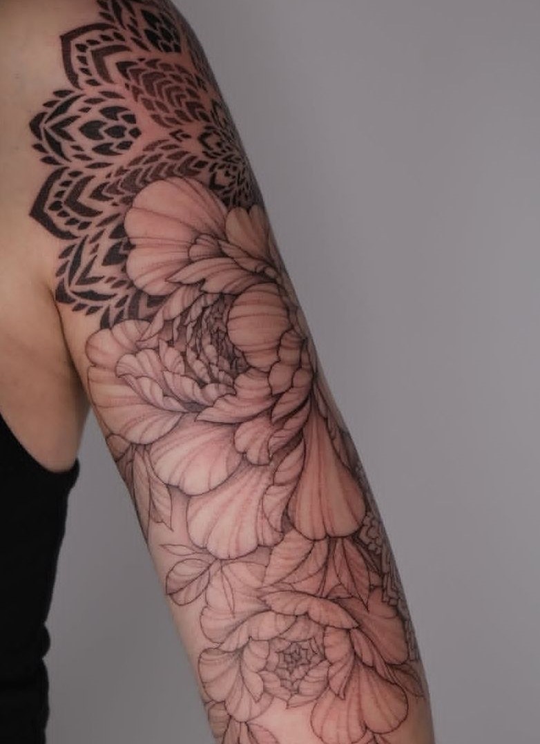 ماندالا و گل‌های رز – سبک فاین‌لاین و بلک‌ورک ترکیب هنری ماندالا روی شانه با گل‌های خطی در امتداد بازو، بسیار شیک و خاص